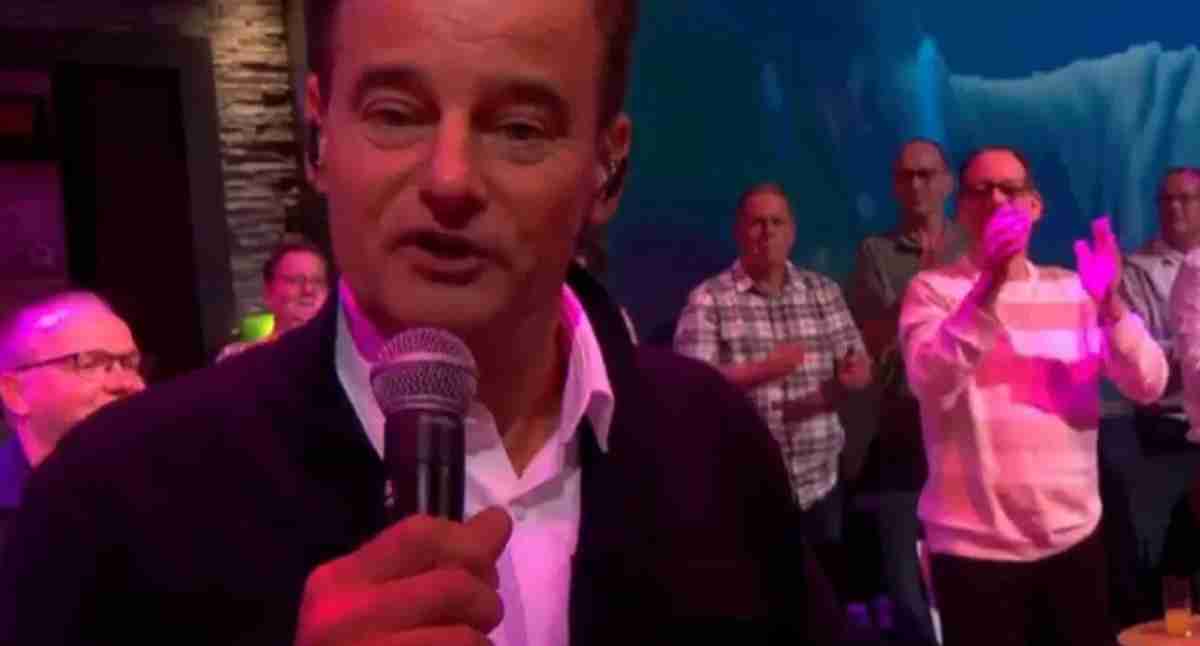 Wilfred Genee zingt met een microfoon in zijn hand voor een volle zaal