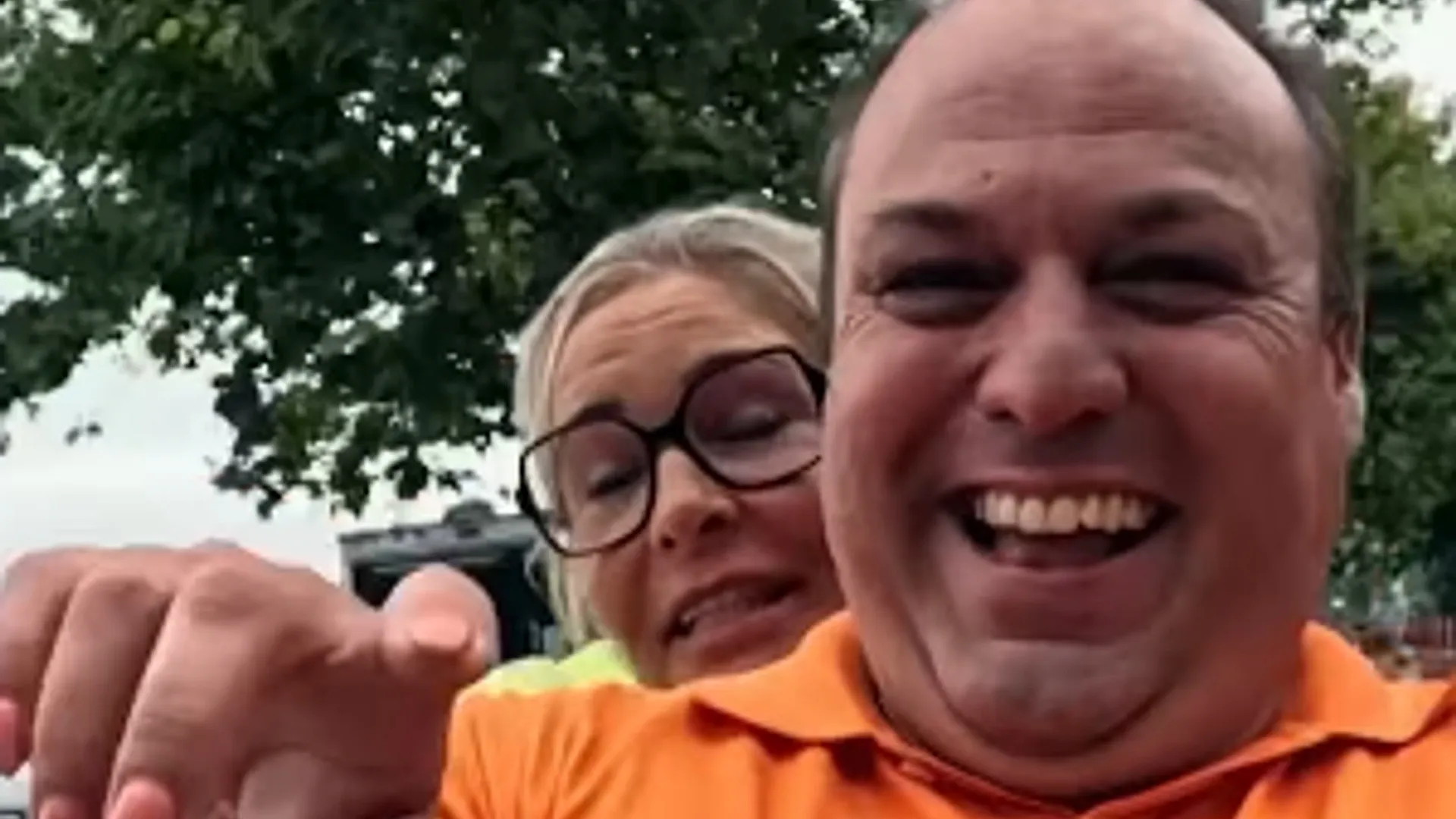 Frans Bauer in oranje poloshirt lacht in de camera met Mariska Bauer naast zich