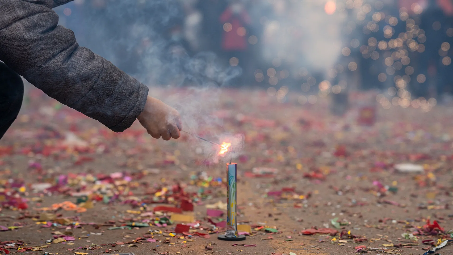 Hand steekt vuurwerk aan tussen confetti