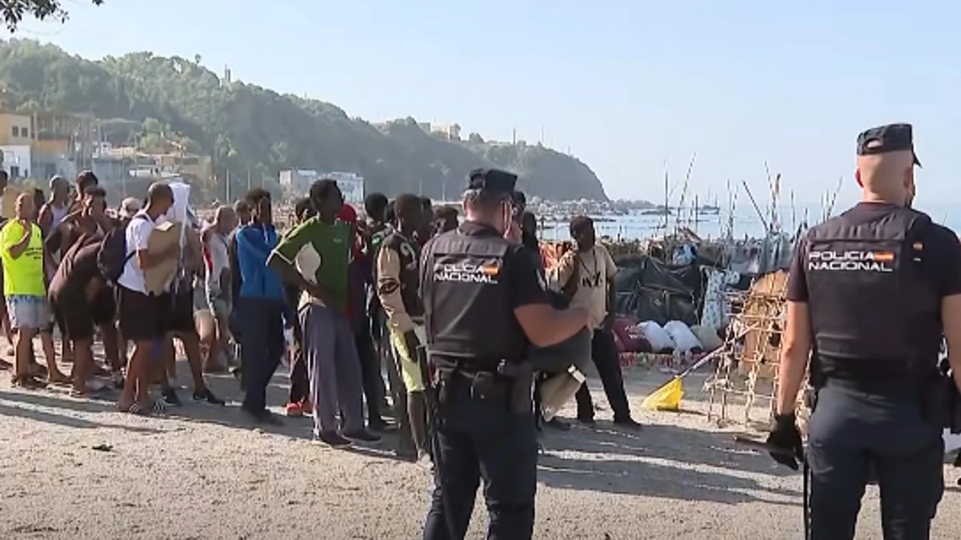 Spaanse agenten bij een groep mensen op het strand van Ceuta