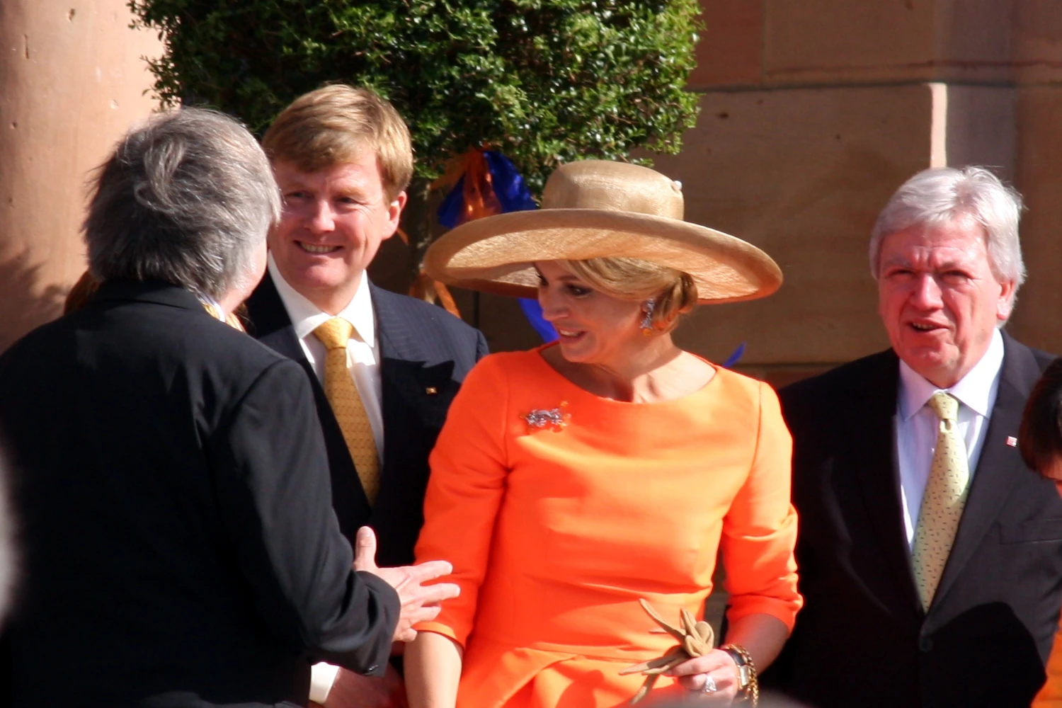 Koningin Maxima met oranje hoed naast koning Willem-Alexander