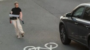 Man loopt over een fietspad naast een geparkeerde auto